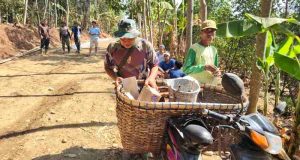 Semangat Anggota Satgas TMMD, Tetap Enjoi Mengendarai Sepeda Motor Sambil Membawa Keranjang Berisi Alat Tukang